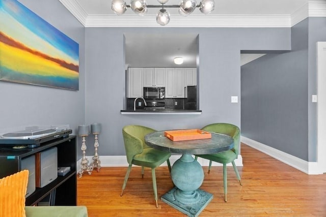 dining area with crown molding, baseboards, and light wood-style flooring