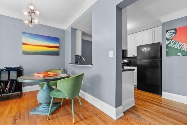 dining space featuring baseboards, an inviting chandelier, ornamental molding, and light wood-style floors