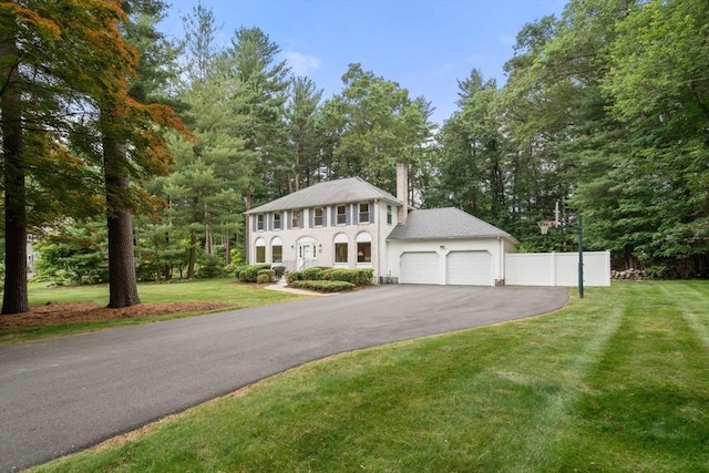 67 Flanagan Dr, Framingham, MA 01701 - colonial house with a garage, driveway, a chimney, and view of wooded area