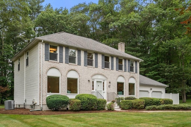 67 Flanagan Dr, Framingham, MA 01701 - view of front of house with a chimney, a garage, a front yard, roof with shingles, and view of scattered trees