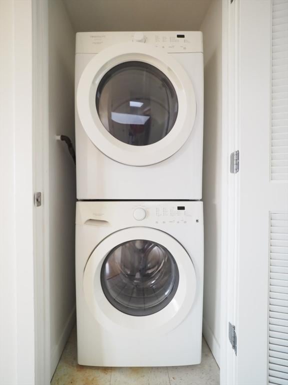 washroom with stacked washer and clothes dryer and light tile patterned flooring