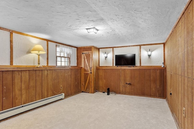 interior space featuring wooden walls, baseboard heating, and a textured ceiling