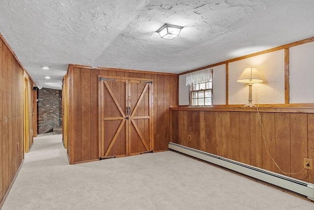 interior space featuring a baseboard heating unit, carpet flooring, wooden walls, and a textured ceiling