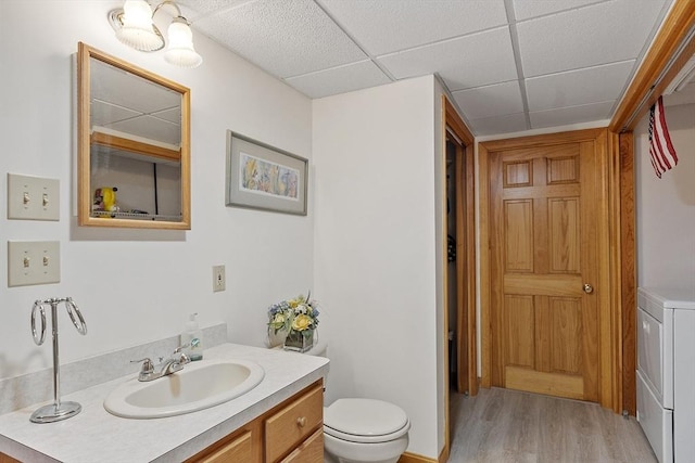 bathroom with vanity, a paneled ceiling, wood finished floors, and toilet