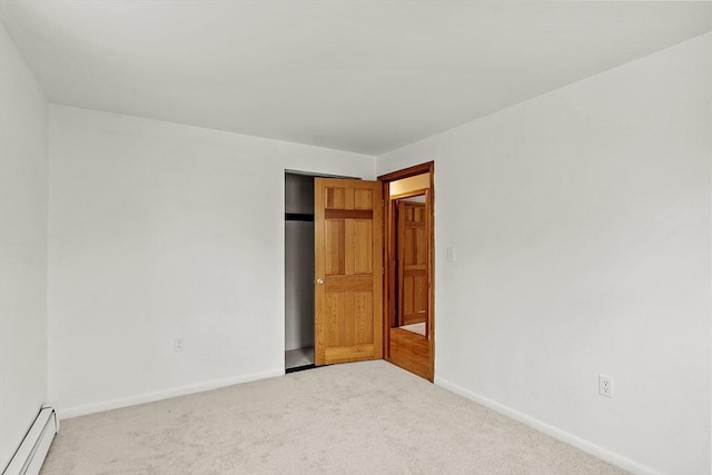 carpeted spare room featuring a baseboard heating unit and baseboards