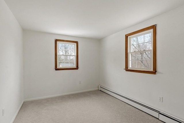 spare room with a baseboard heating unit, baseboards, and light colored carpet