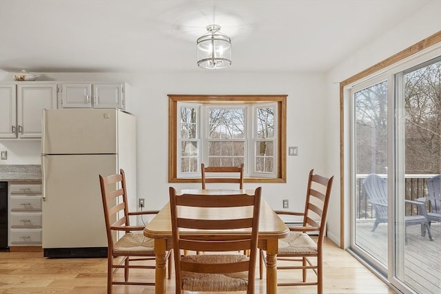 dining area with light wood finished floors and an inviting chandelier