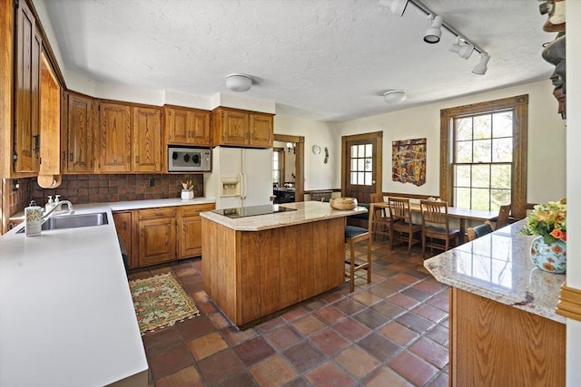 185 Woodland St, Natick, MA 01760 - kitchen with stainless steel microwave, white refrigerator with ice dispenser, black electric cooktop, a sink, and a kitchen island