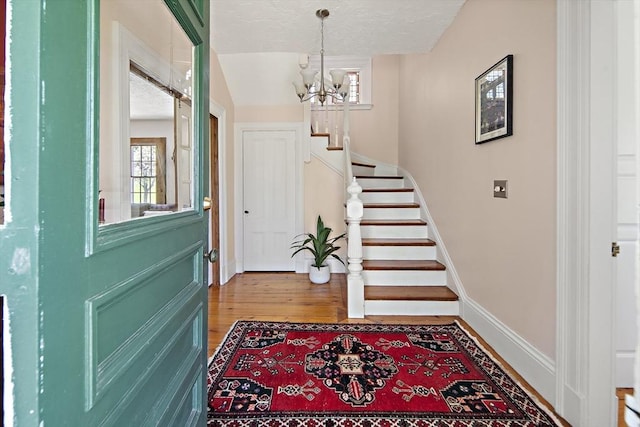185 Woodland St, Natick, MA 01760 - entrance foyer with a chandelier, wood finished floors, stairs, baseboards, and a textured ceiling