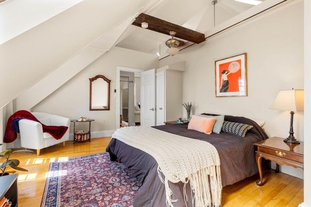 bedroom featuring baseboards, light wood-style flooring, and lofted ceiling with beams
