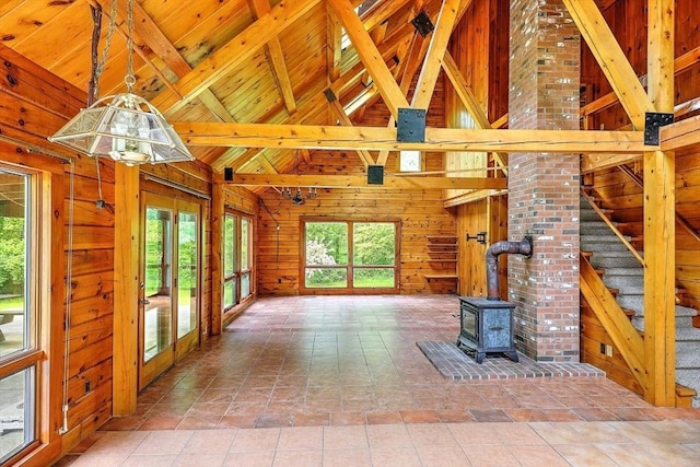 1175 Main Rd, Westport, MA 02790 - unfurnished living room featuring wooden walls, a wood stove, healthy amount of natural light, wooden ceiling with exposed beams, and high vaulted ceiling