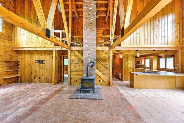 1175 Main Rd, Westport, MA 02790 - unfurnished living room with high vaulted ceiling, wooden walls, a wood stove, and beamed ceiling