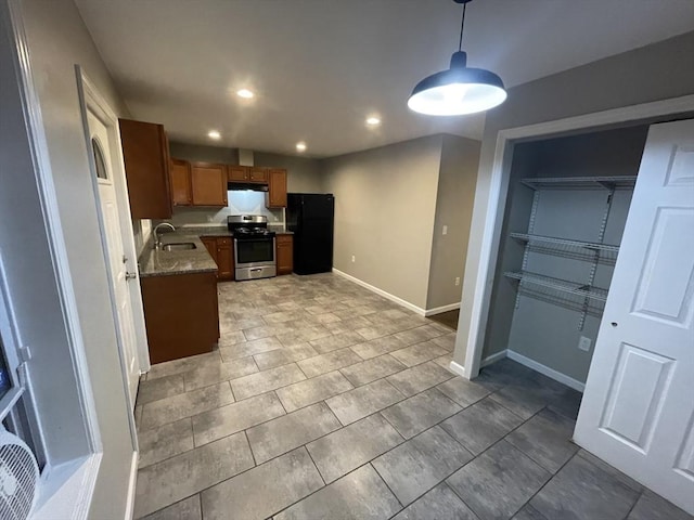 kitchen featuring sink, stone counters, hanging light fixtures, black fridge, and gas range