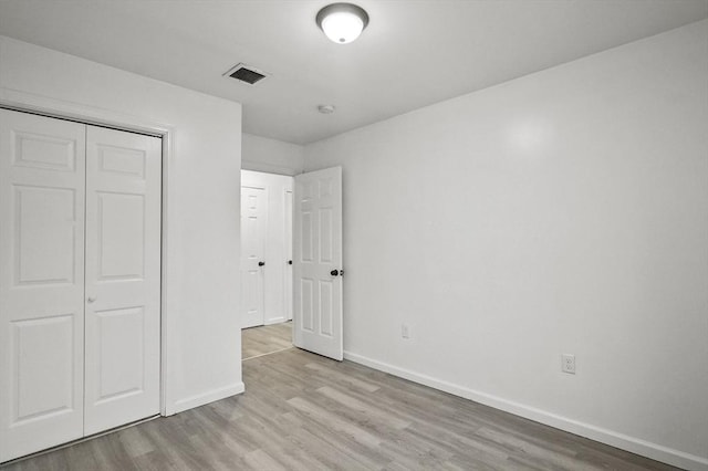 unfurnished bedroom featuring a closet and light wood-type flooring