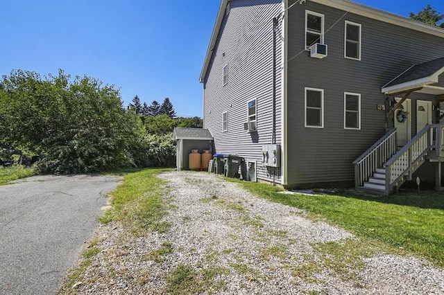 view of property exterior with a storage unit and a lawn