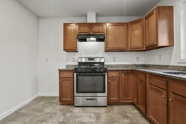 kitchen with dark stone countertops, sink, exhaust hood, and gas stove