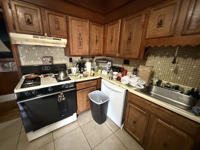 156 Euclid Ave, Lynn, MA 01904 - kitchen featuring gas stove, under cabinet range hood, white dishwasher, decorative backsplash, and brown cabinetry