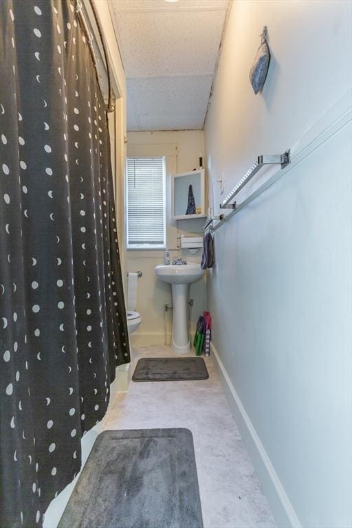 bathroom with toilet, curtained shower, sink, and a drop ceiling