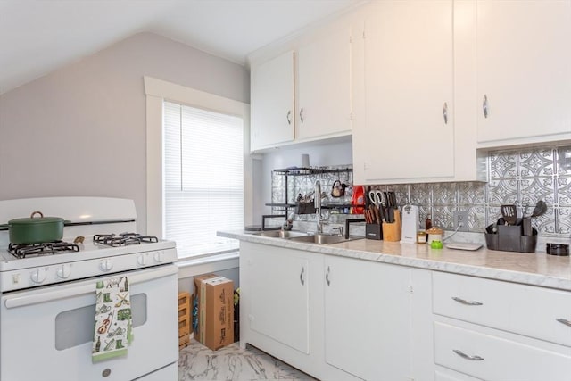 kitchen featuring lofted ceiling, sink, white cabinets, white gas range, and decorative backsplash