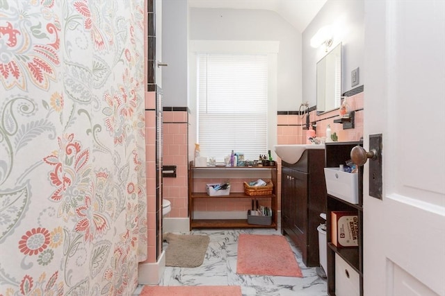 bathroom with tile walls, vanity, curtained shower, and lofted ceiling