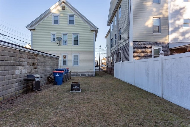 rear view of property featuring an outdoor fire pit and a yard