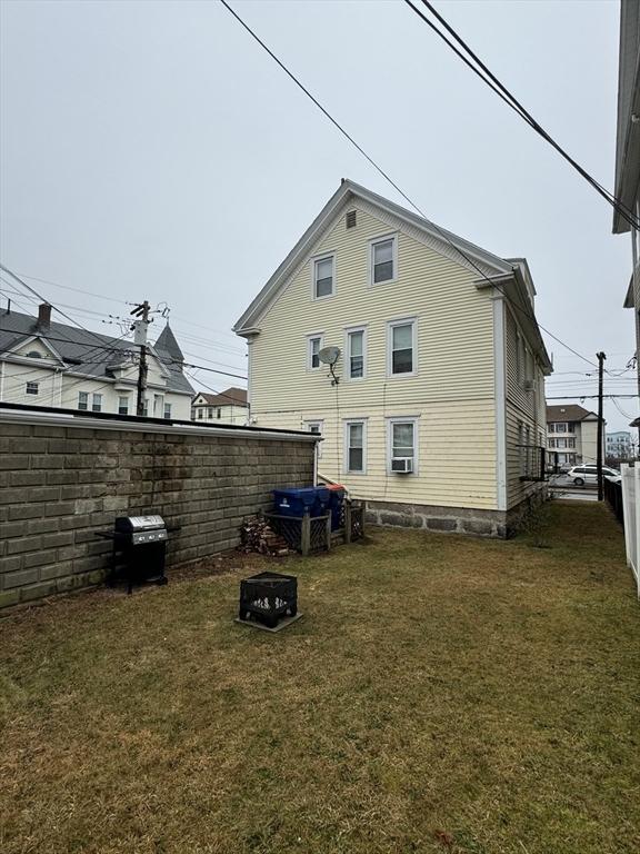 rear view of house with an outdoor fire pit and a yard