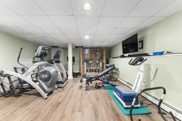exercise area with a paneled ceiling, wood finished floors, recessed lighting, and baseboard heating