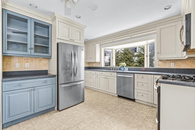 kitchen featuring dark countertops, appliances with stainless steel finishes, decorative backsplash, and glass insert cabinets