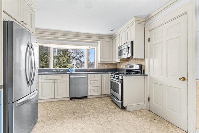 kitchen featuring appliances with stainless steel finishes, dark countertops, a sink, and white cabinetry