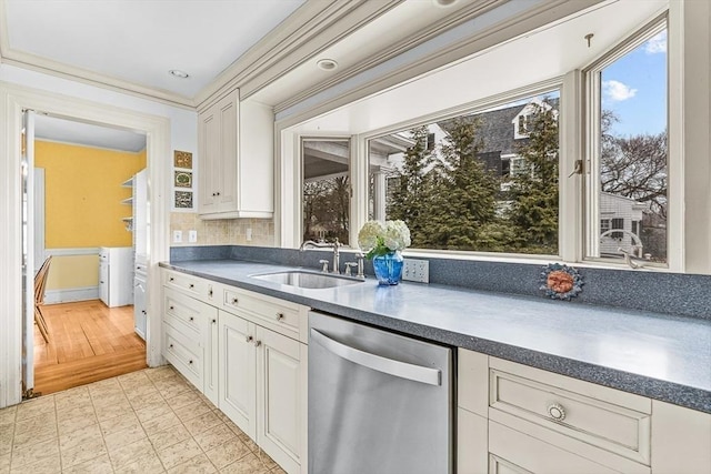 kitchen featuring dark countertops, white cabinets, dishwasher, and a sink