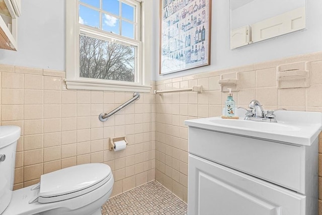 bathroom with tile walls, a wainscoted wall, vanity, and toilet