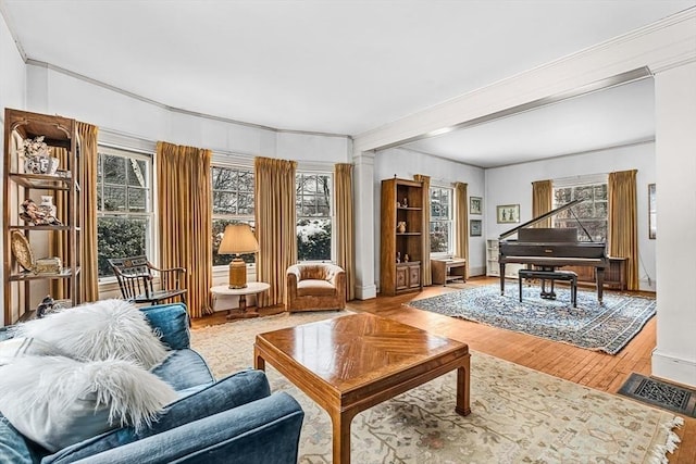 sitting room with a healthy amount of sunlight, crown molding, visible vents, and wood finished floors