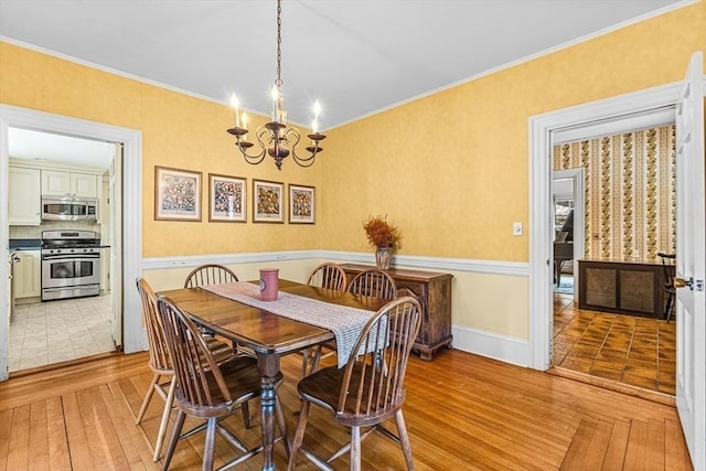 dining area featuring light wood-style floors, a notable chandelier, crown molding, and baseboards