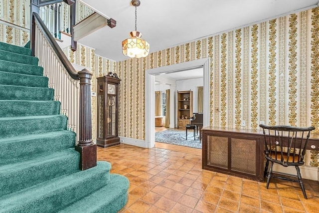 foyer entrance with wallpapered walls, stairs, and baseboards