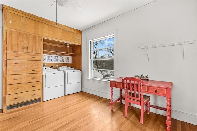 washroom featuring laundry area, baseboards, washer and clothes dryer, and wood finished floors