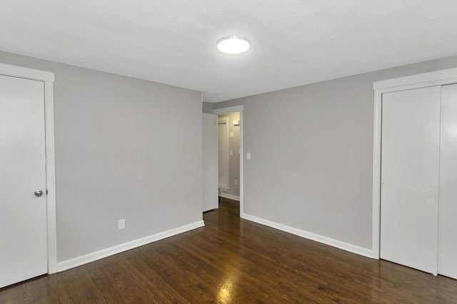 unfurnished bedroom with wood finished floors, baseboards, and a closet