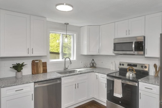 kitchen featuring stainless steel appliances, a sink, white cabinets, and backsplash