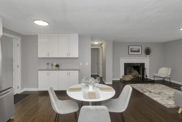 dining room featuring baseboards, dark wood finished floors, and a premium fireplace