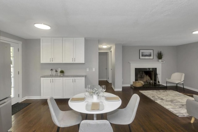 dining room with baseboards, dark wood-style flooring, and a premium fireplace