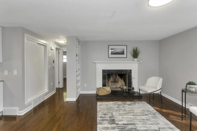living area featuring wood finished floors, a fireplace, and baseboards