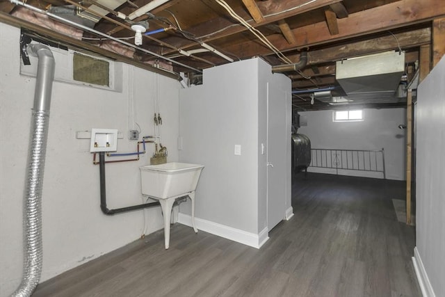 below grade area with dark wood-type flooring, oil tank, and baseboards