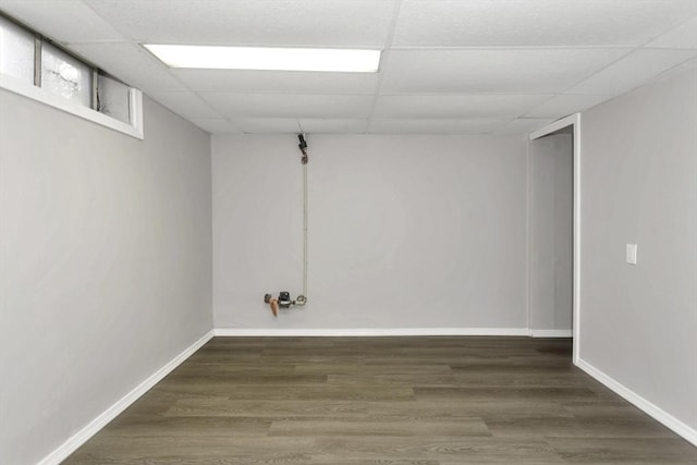 finished basement with a paneled ceiling, wood finished floors, and baseboards