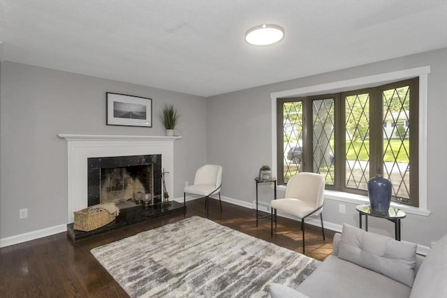 living area with baseboards, a fireplace, and wood finished floors