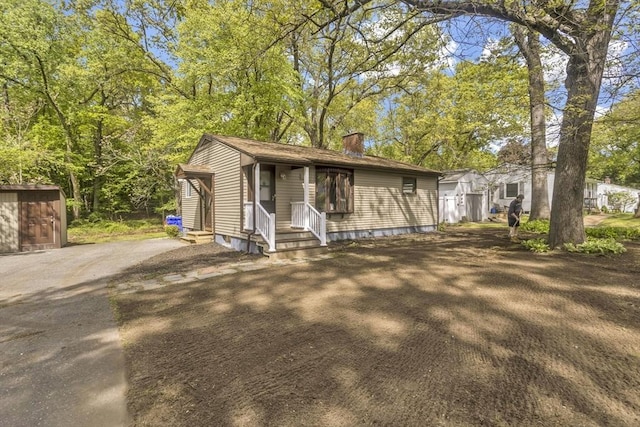 view of front facade featuring a chimney, entry steps, and asphalt driveway