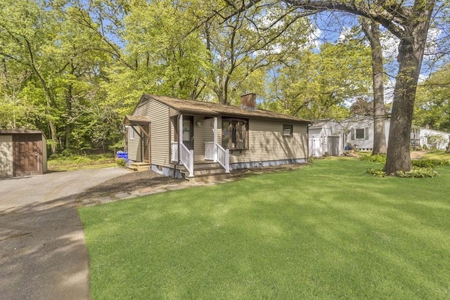 view of front of home featuring a chimney, a front yard, entry steps, and asphalt driveway