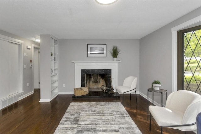 living area with wood finished floors, baseboards, built in shelves, and a premium fireplace