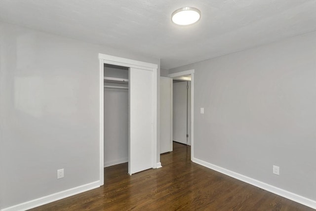 unfurnished bedroom featuring a closet, wood finished floors, and baseboards