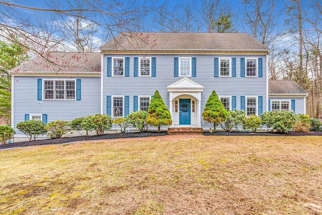 view of front of house with a shingled roof and a front lawn