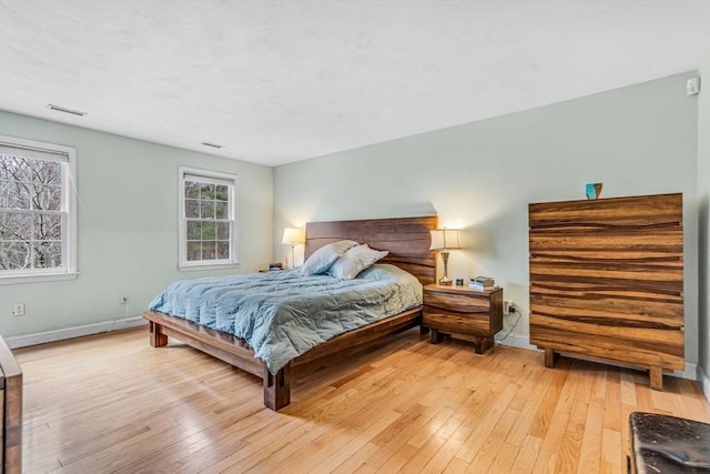 bedroom featuring baseboards, light wood finished floors, and visible vents