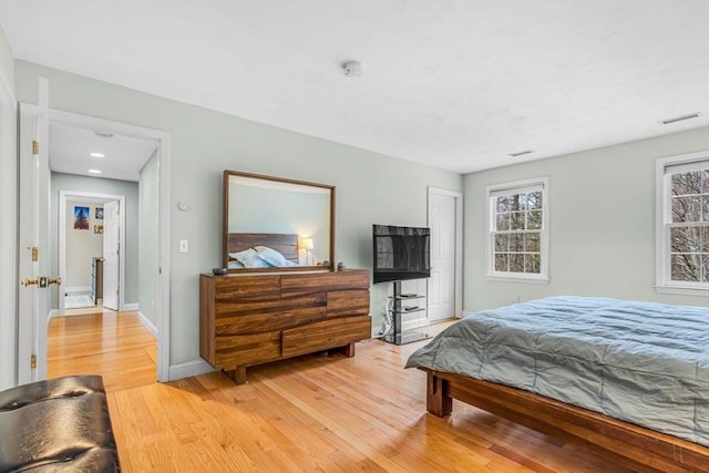 bedroom with multiple windows, light wood finished floors, and visible vents